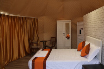 Cozy interior of a premium dome tent with a bed, wardrobe, and seating area.