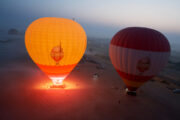 Hot air balloon floating over the Dubai desert at sunrise.