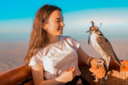 Woman holding a falcon inside a hot air balloon basket.