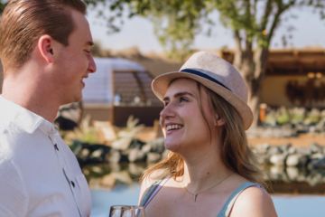 Couple enjoying a romantic lakeside moment at a luxurious desert retreat.