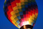 A colorful hot air balloon floating above the Dubai desert at sunrise