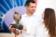 A couple enjoying a falconry experience in the Dubai desert, with a falcon perched on their hand.