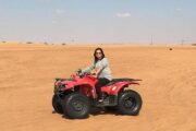 Adventurous woman riding a red quad bike in the Dubai desert