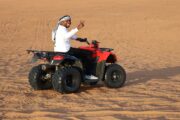 Man riding a red Suzuki quad bike in the desert