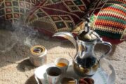 A traditional Arabian coffee pot (dallah) and dates arranged on a woven mat.