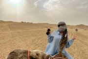 Woman enjoying a camel ride during sunset in the Dubai desert