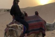 Woman enjoying a camel ride during sunset in the Dubai desert