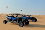 Can-Am Maverick X3 buggy racing across the desert with a helmeted driver.