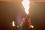 A fire performer dramatically consuming a flame in a nighttime show.