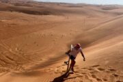 A woman holding a sandboard in Dubai desert