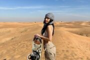 A woman holding a sandboard in Dubai desert