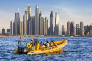 A bright yellow tour boat cruising near Dubai’s skyscraper-lined marina.