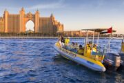 A bright yellow tour boat cruising through Dubai Marina, framed by modern skyscrapers.