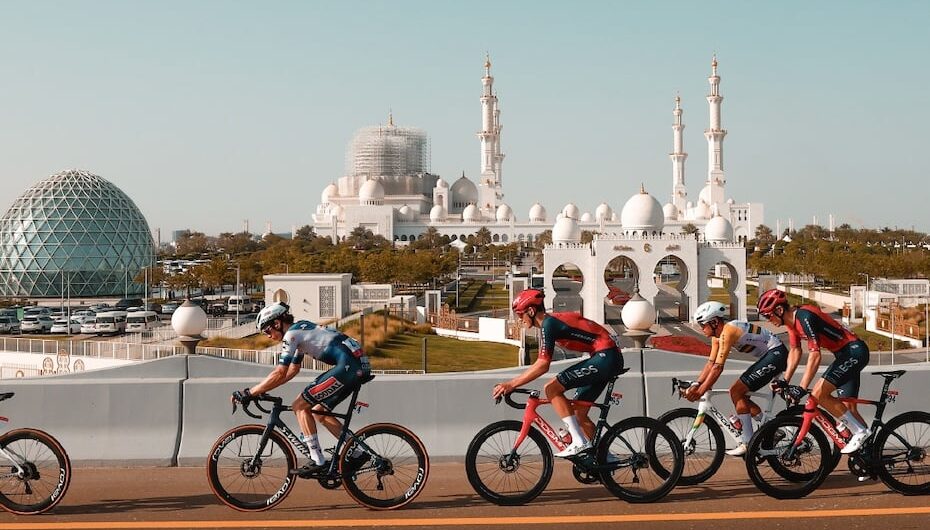 Professional cyclists riding past the Sheikh Zayed Grand Mosque in Abu Dhabi during a race.