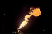 A fire performer breathing a large flame into the night sky.