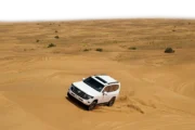 4×4 Jeep blasting across golden desert dunes at high speed.