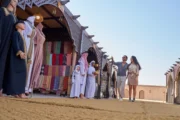 A traditional desert camp with low seating and decorative lanterns under twilight.