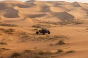 A dune buggy driving through expansive desert dunes, showcasing the rolling terrain.