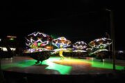 A group of Tanoura dancers spinning in LED-lit skirts on an outdoor stage.