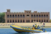 A bright yellow tour boat carrying passengers near Yas Bay Waterfront.