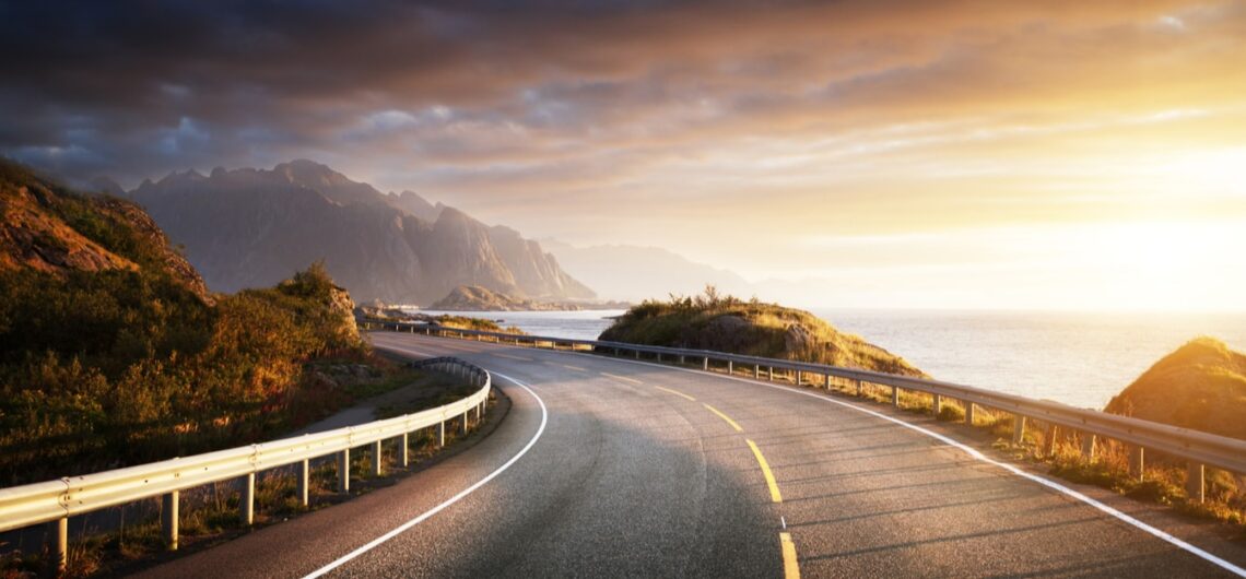 Scenic coastal road at sunset with mountains and ocean views