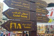Direction signs pointing to various traditional souks in Dubai, including Gold Souq and Textile Souq
