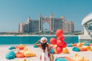 Woman holding red balloons on beach with Atlantis The Palm in the background