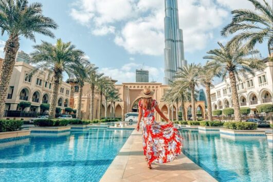 Woman in floral dress walking toward Burj Khalifa in Downtown Dubai