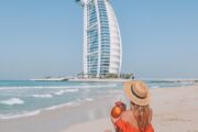 Woman enjoying fresh coconut by the beach with Burj Al Arab in the background