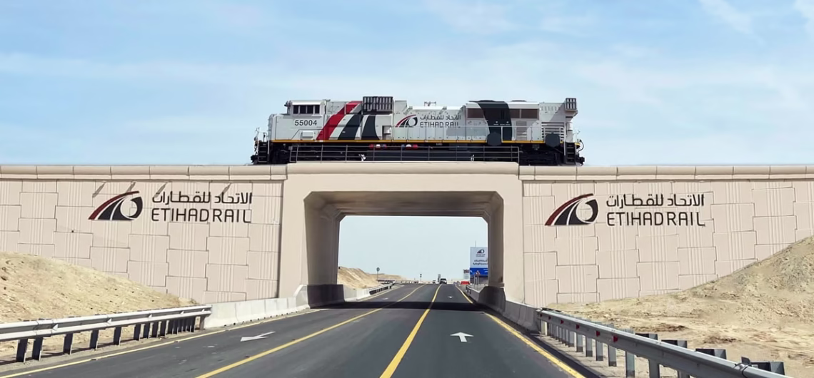 Etihad Rail passenger and freight trains running side by side through the UAE desert.