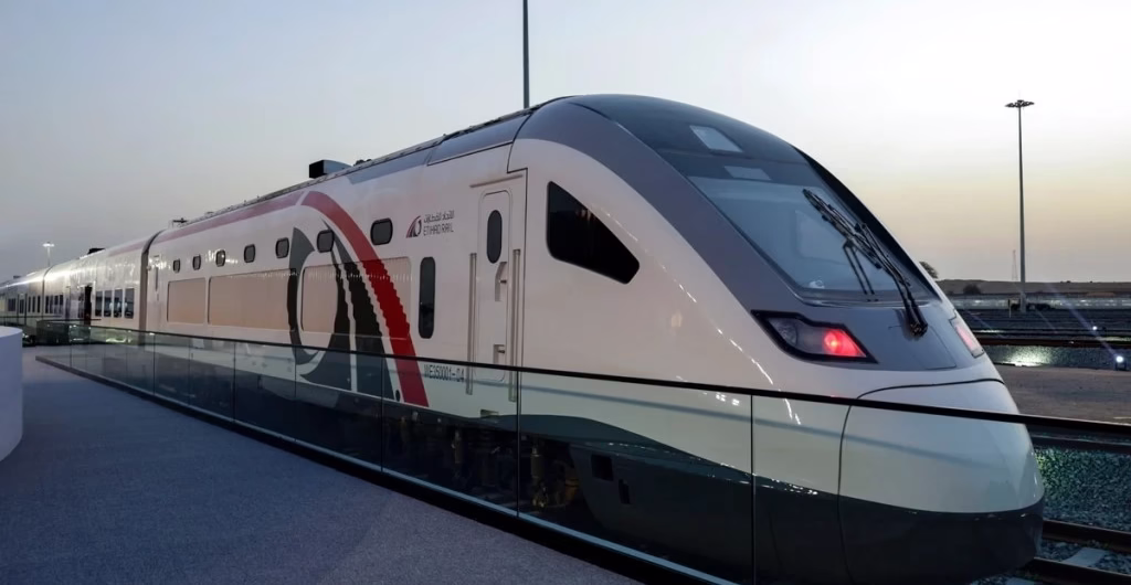 Modern Etihad Rail passenger train at a station in the UAE during sunset.