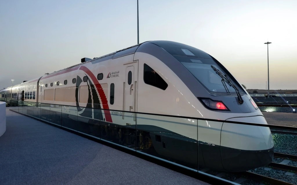 Modern Etihad Rail passenger train at a station in the UAE during sunset.