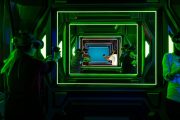 Players in VR laser tag arena with glowing green lights.