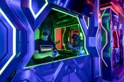 Players inside VR shooting booths with neon green and red lighting.