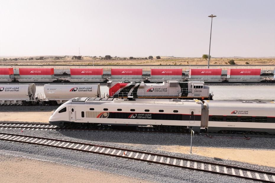 Etihad Rail passenger and freight trains running parallel in the desert.