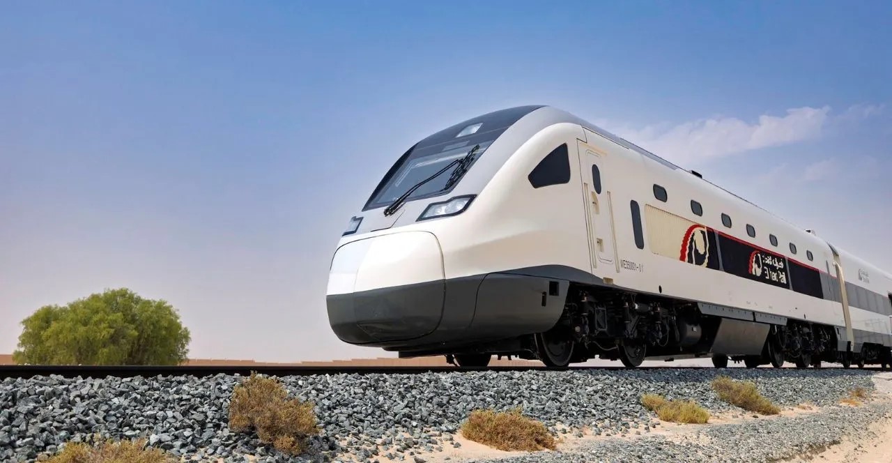 Modern Etihad Rail passenger train traveling through the UAE desert.