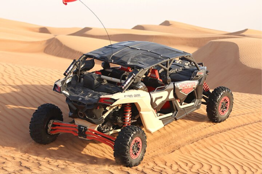 Dune buggy Can-Am Maverick Turbo rosso che gareggia sulla sabbia del deserto