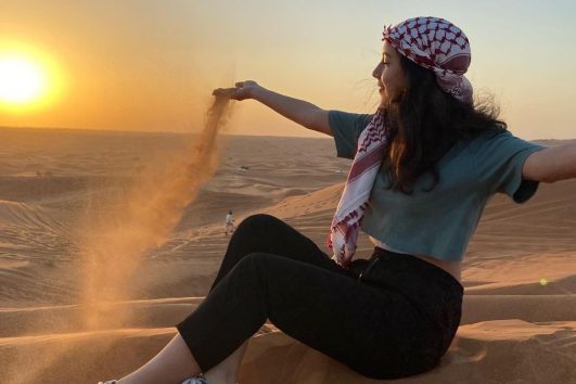 Woman pouring sand during sunset in Dubai desert safari