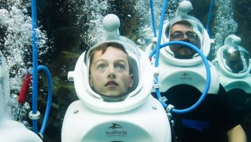 visitors walking underwater with helmet diving experience at SeaWorld