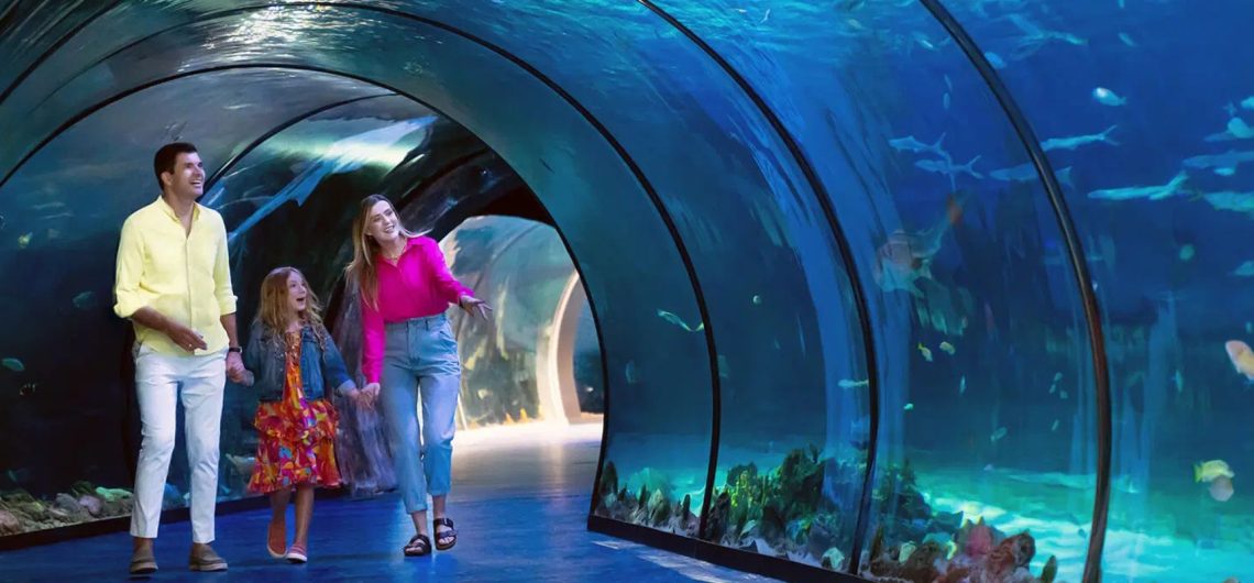 family walking inside Dubai Aquarium tunnel surrounded by sharks and marine life Dubai Mall