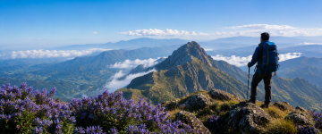 Trekker standing on a mountain summit overlooking dramatic peaks and valleys in Kerala.