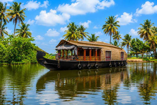 Una tradizionale e lussuosa casa galleggiante naviga tra le tranquille lagune di Alleppey, circondata da palme da cocco, nel Kerala.