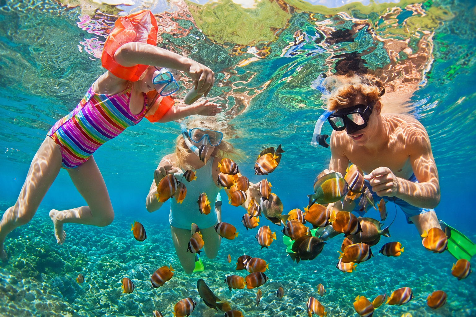 Una famiglia fa snorkeling tra coloratissimi pesci tropicali nelle acque cristalline delle Isole Andamane.
