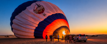 Crew inflating a hot air balloon before sunrise in the Dubai desert.