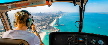 Passenger enjoying breathtaking aerial views of Burj Al Arab and Dubai coastline from inside a helicopter.
