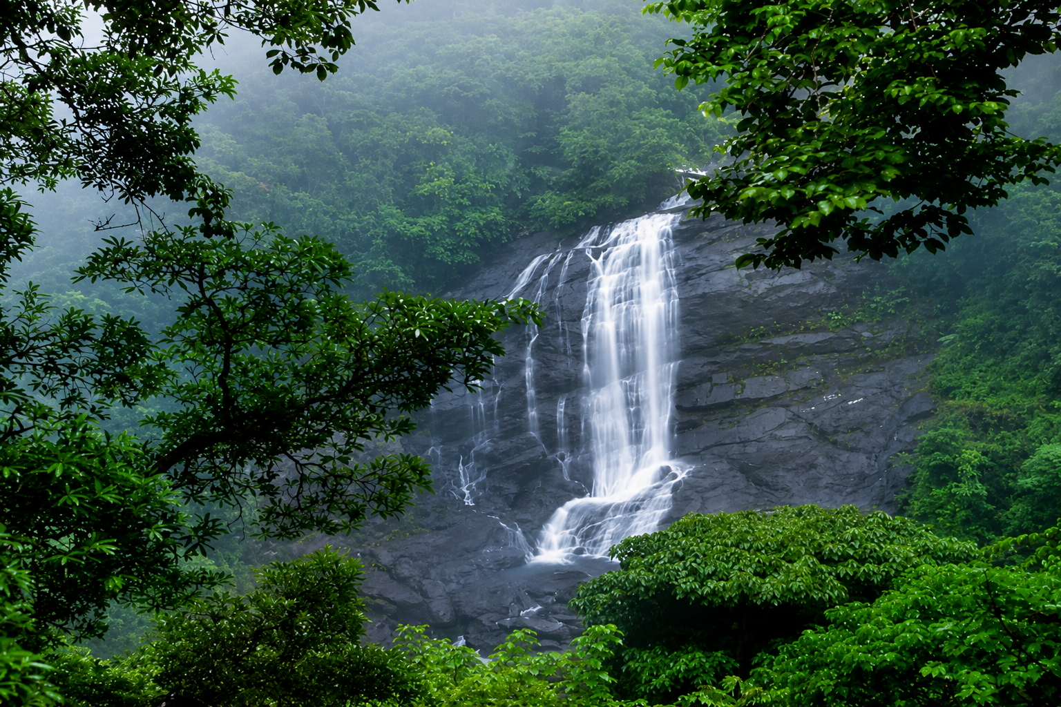 Beautiful Valara Waterfalls cascading through dense tropical rainforest in Kerala.