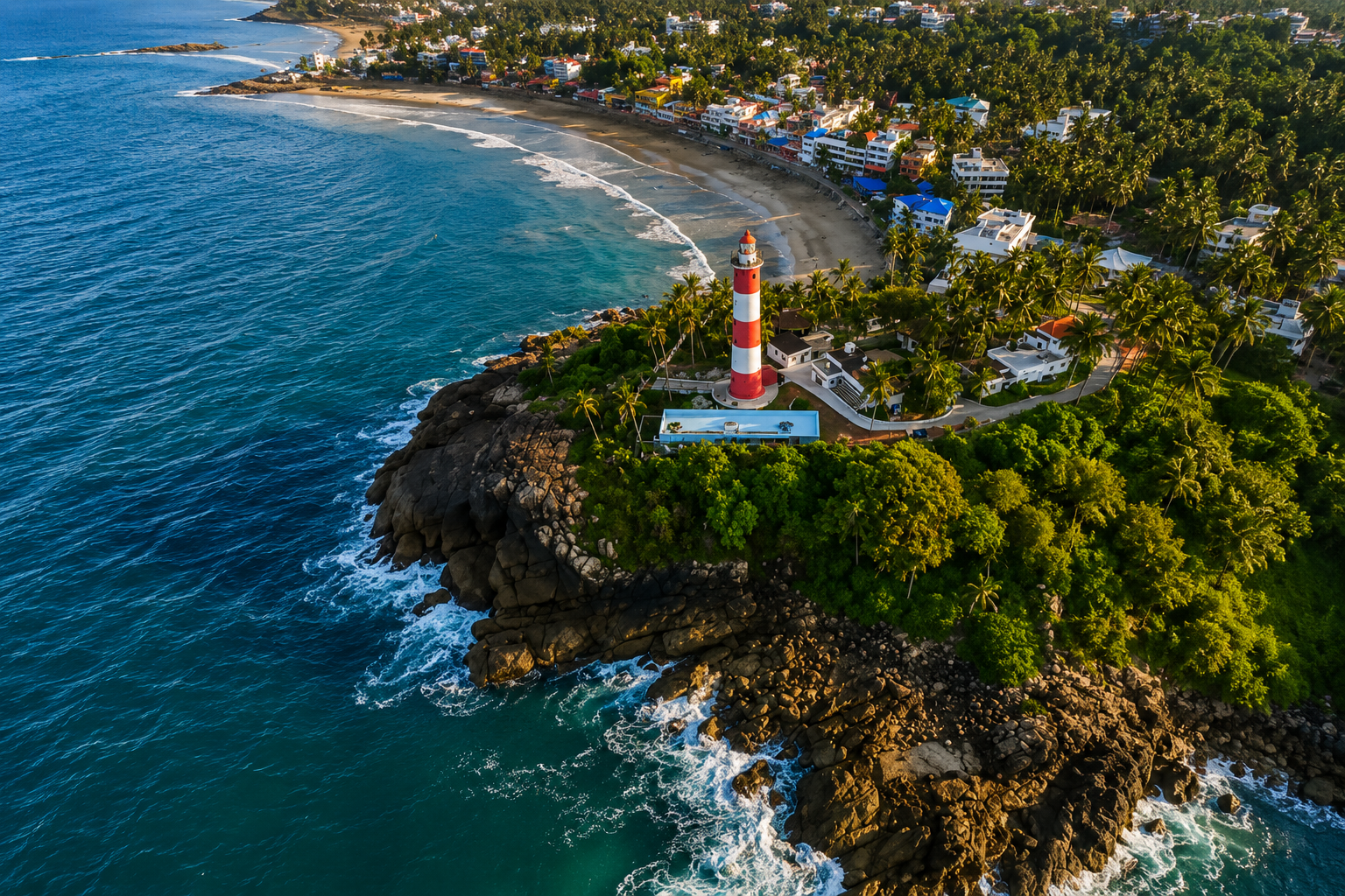 Red and white Vizhinjam Lighthouse overlooking rocky shoreline, fishing boats, and Arabian Sea waves at Kovalam Beach, Kerala.